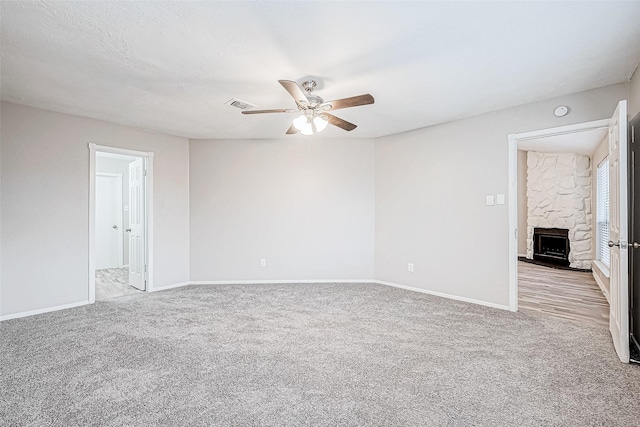 spare room with ceiling fan, light carpet, and a fireplace