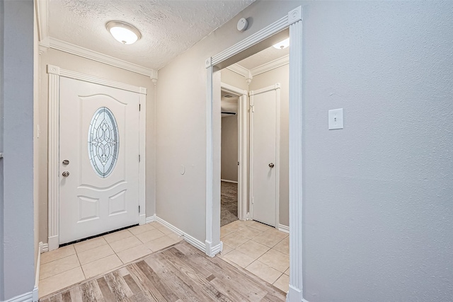 entryway featuring ornamental molding, light hardwood / wood-style floors, and a textured ceiling