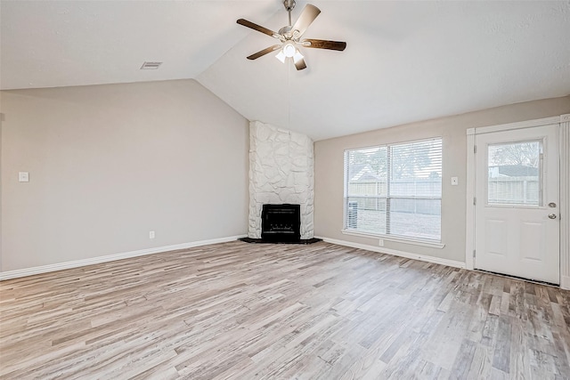 unfurnished living room featuring lofted ceiling, light hardwood / wood-style floors, ceiling fan, and a stone fireplace