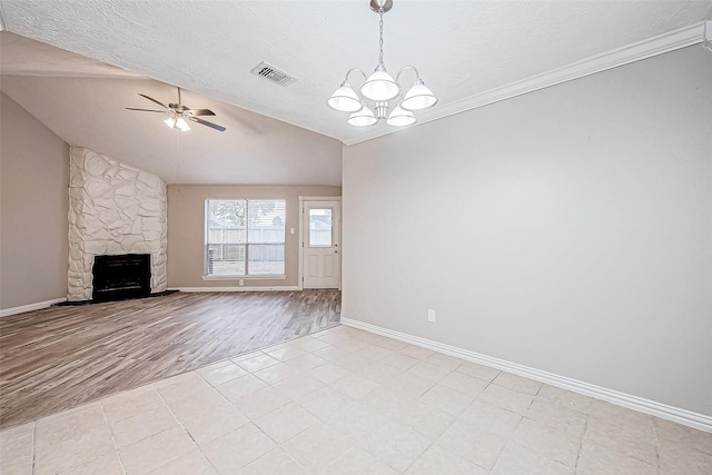 unfurnished living room featuring lofted ceiling, ceiling fan with notable chandelier, a textured ceiling, and a stone fireplace