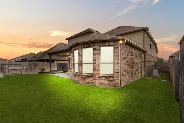 property exterior at dusk with a patio and a lawn