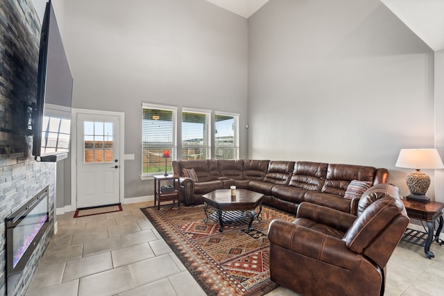 living room featuring plenty of natural light, a towering ceiling, light tile patterned floors, and a fireplace