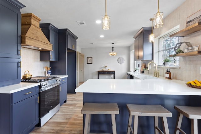 kitchen with stainless steel gas stove, premium range hood, a kitchen bar, and decorative backsplash