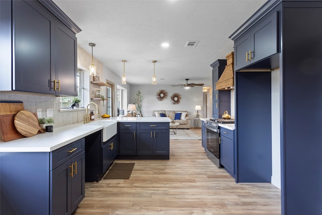 kitchen featuring pendant lighting, stainless steel range oven, sink, kitchen peninsula, and light wood-type flooring