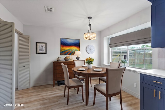 dining space with light hardwood / wood-style flooring and an inviting chandelier