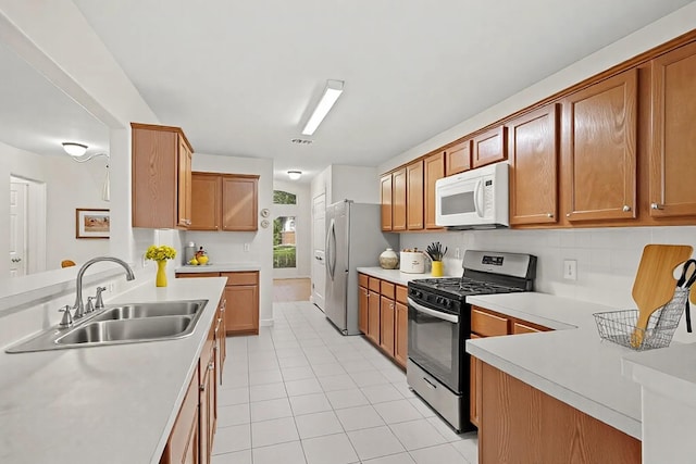 kitchen with kitchen peninsula, appliances with stainless steel finishes, sink, light tile patterned floors, and decorative backsplash