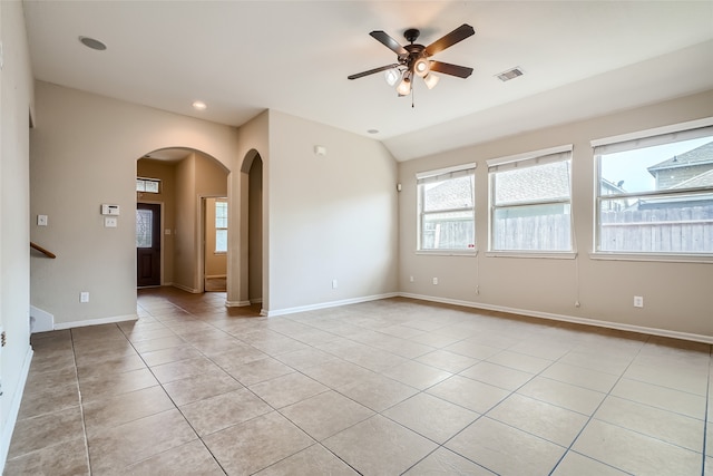 empty room with ceiling fan, vaulted ceiling, and light tile patterned flooring