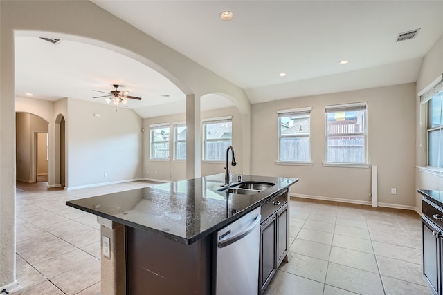 kitchen with dishwasher, sink, dark stone countertops, a center island with sink, and lofted ceiling