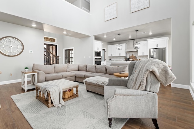 living room with a towering ceiling and dark hardwood / wood-style floors