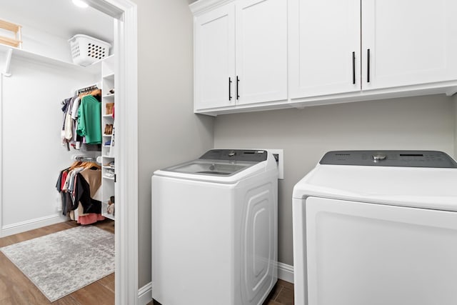 clothes washing area with dark wood-type flooring, cabinets, and washing machine and clothes dryer