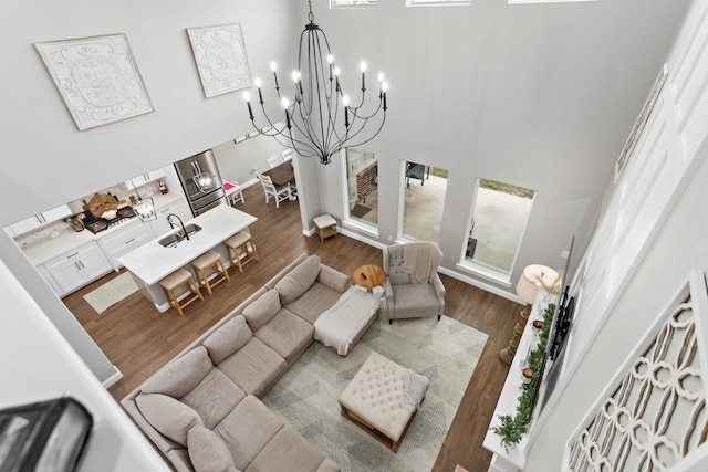 living room with sink, a notable chandelier, a high ceiling, and dark wood-type flooring