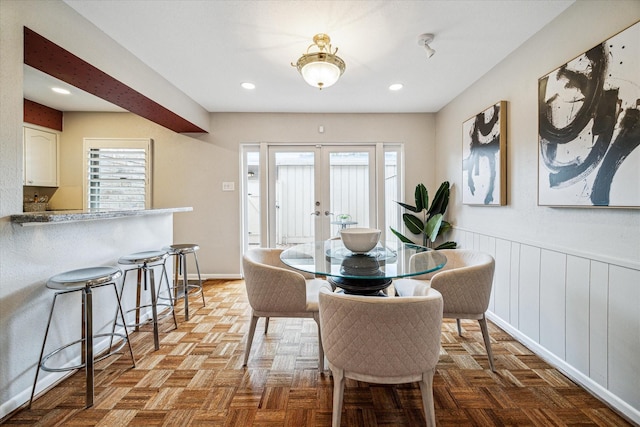 dining space with a wainscoted wall, recessed lighting, baseboards, and french doors