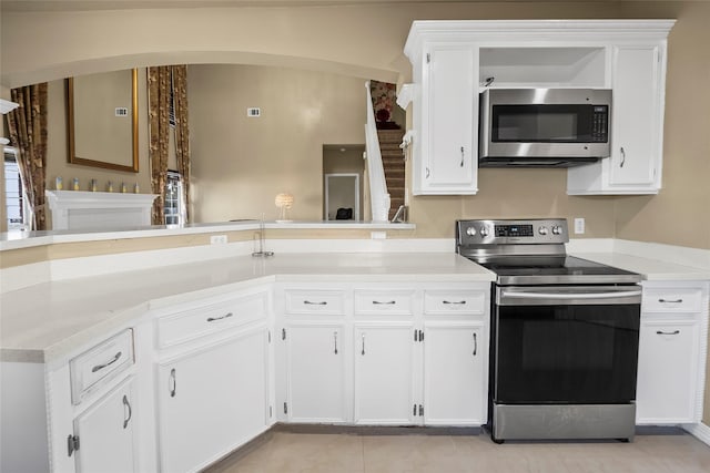 kitchen featuring light tile patterned floors, kitchen peninsula, white cabinets, and stainless steel appliances