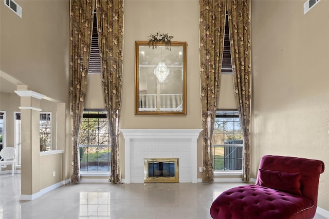 living area featuring a high ceiling, ornate columns, and a fireplace