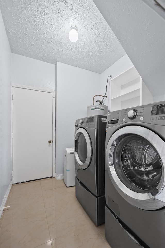 washroom with light tile patterned floors, a textured ceiling, washer and clothes dryer, and water heater