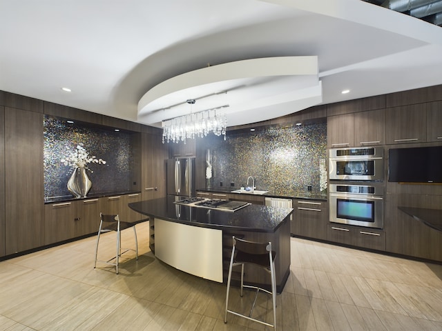 kitchen featuring hanging light fixtures, appliances with stainless steel finishes, sink, a center island, and a breakfast bar