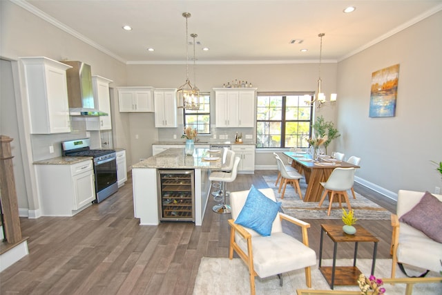 kitchen featuring pendant lighting, white cabinets, wall chimney range hood, gas stove, and beverage cooler