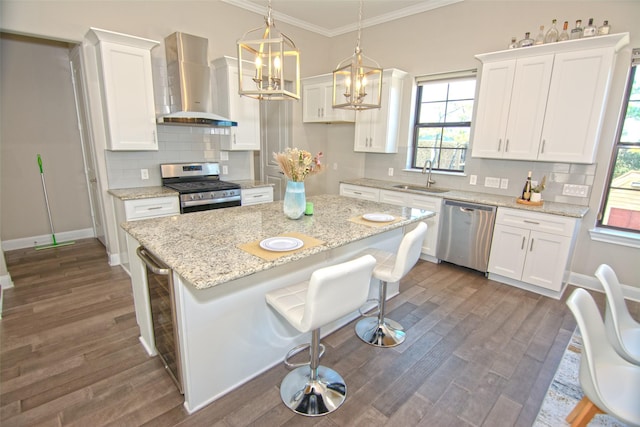 kitchen with wall chimney exhaust hood, white cabinets, a breakfast bar, and stainless steel appliances