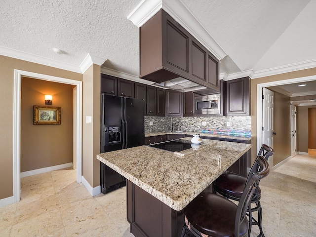 kitchen featuring dark brown cabinets, tasteful backsplash, light stone counters, a center island, and black appliances