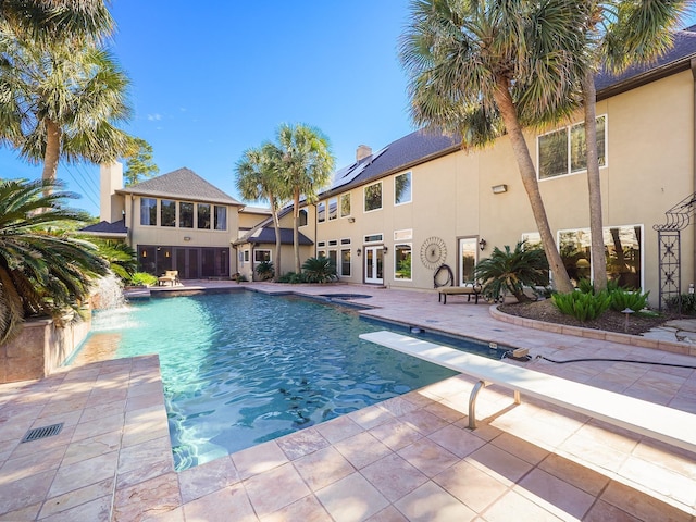 view of swimming pool with pool water feature and a diving board