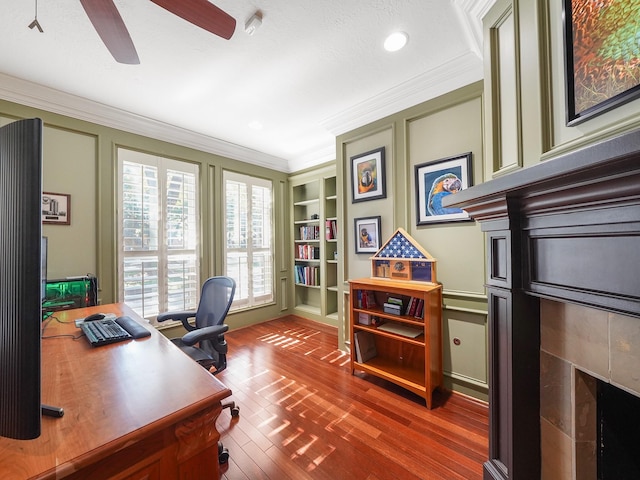 home office featuring hardwood / wood-style flooring, built in features, crown molding, and ceiling fan