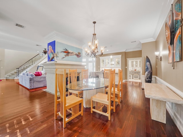 dining room featuring dark hardwood / wood-style flooring, ornamental molding, and a chandelier