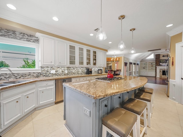 kitchen featuring white cabinets, a center island, appliances with stainless steel finishes, sink, and crown molding