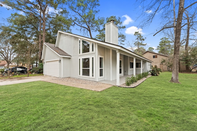 back of property featuring a garage, concrete driveway, a chimney, and a lawn