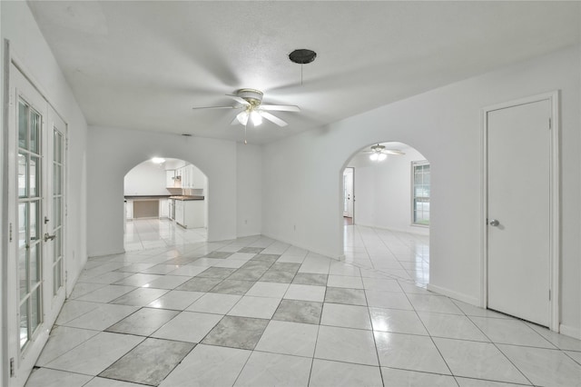 empty room with a textured ceiling, light tile patterned floors, and ceiling fan