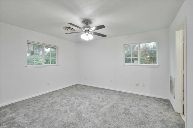 carpeted spare room featuring ceiling fan and plenty of natural light