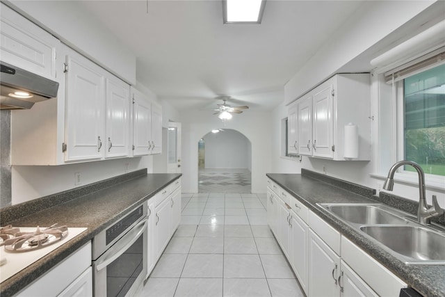 kitchen with sink, light tile patterned flooring, white cabinetry, and oven