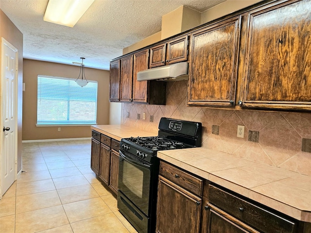 kitchen featuring pendant lighting, tile counters, gas stove, backsplash, and light tile patterned floors