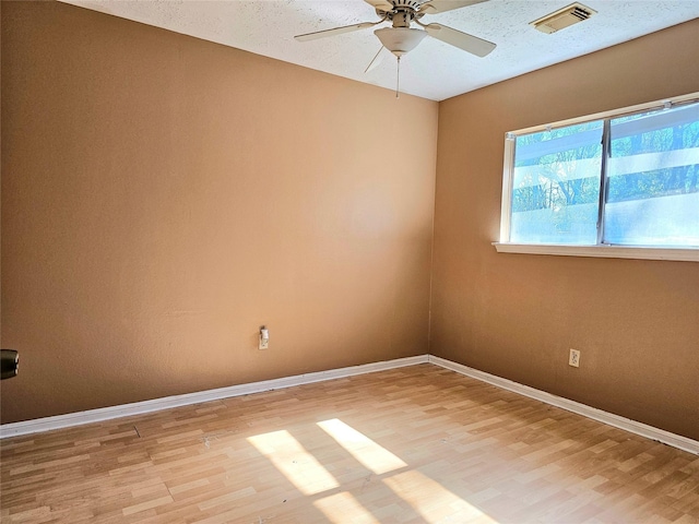 empty room with ceiling fan, light hardwood / wood-style flooring, and a textured ceiling