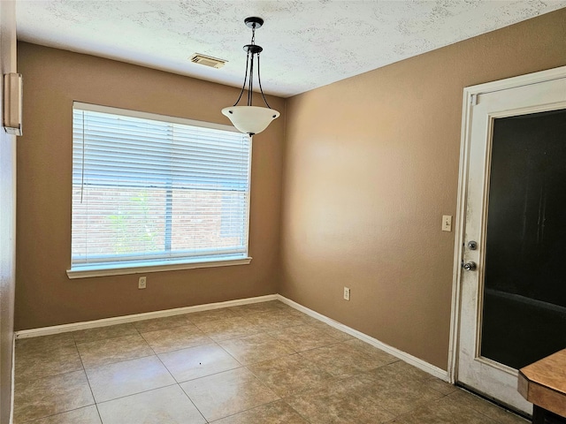 unfurnished dining area with tile patterned floors and a textured ceiling