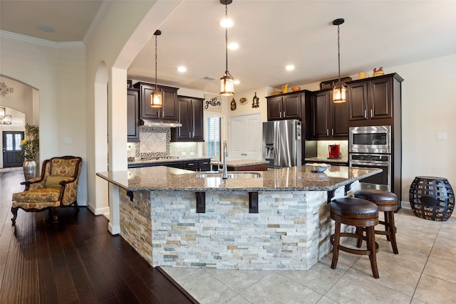 kitchen featuring stainless steel appliances, hanging light fixtures, a large island, and a kitchen breakfast bar