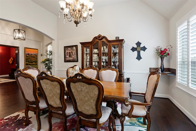 dining area with dark wood-type flooring, a chandelier, and vaulted ceiling