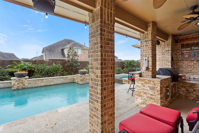 view of swimming pool featuring a patio area, an outdoor kitchen, exterior bar, ceiling fan, and area for grilling