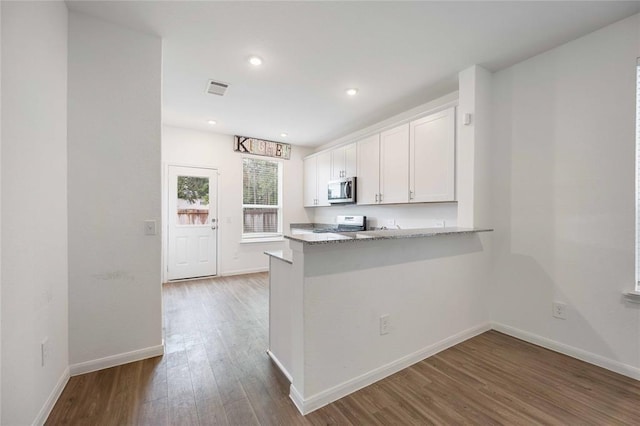 kitchen featuring white cabinets, kitchen peninsula, stainless steel appliances, light stone counters, and dark hardwood / wood-style floors