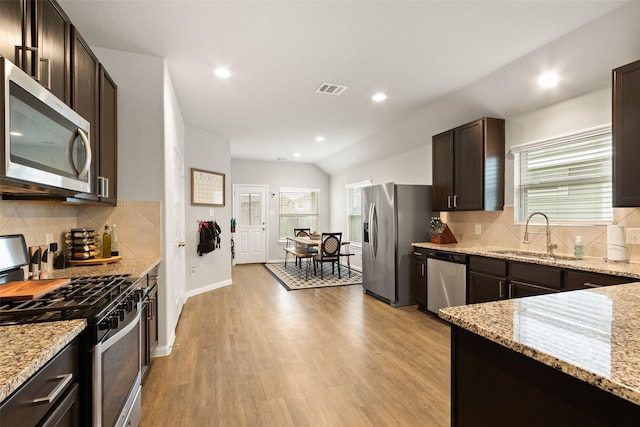 kitchen featuring appliances with stainless steel finishes, sink, light stone counters, light hardwood / wood-style flooring, and dark brown cabinets