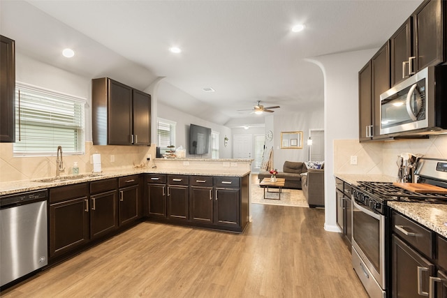 kitchen with sink, stainless steel appliances, light hardwood / wood-style floors, and backsplash