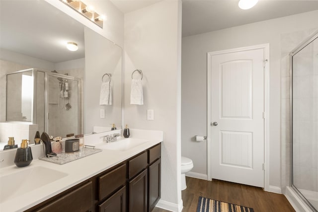 bathroom featuring hardwood / wood-style flooring, toilet, a shower with shower door, and vanity