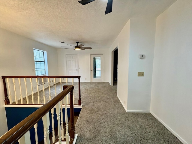 corridor featuring dark carpet and a textured ceiling