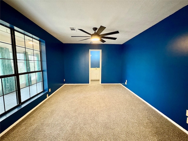 carpeted empty room featuring ceiling fan and a textured ceiling