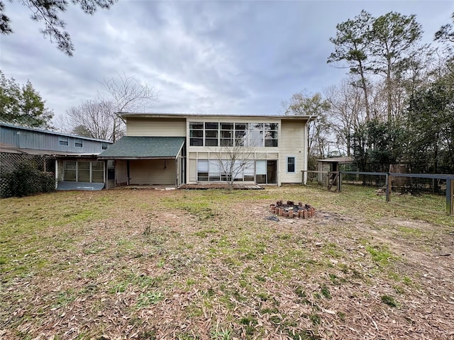 rear view of property with a lawn and an outdoor fire pit