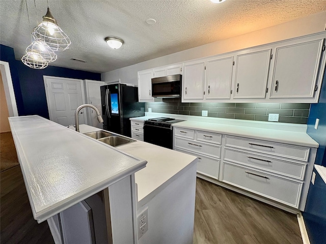 kitchen with sink, a kitchen island with sink, black appliances, decorative backsplash, and decorative light fixtures