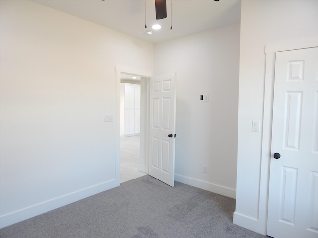 unfurnished bedroom featuring light colored carpet, ceiling fan, and baseboards