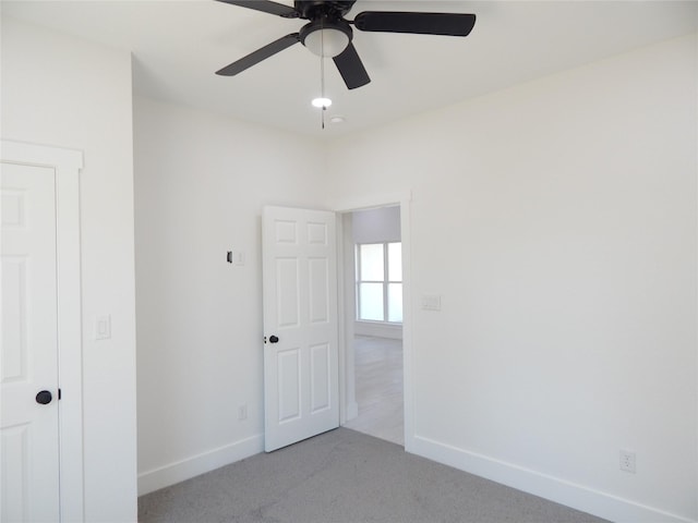 unfurnished bedroom with baseboards, a ceiling fan, and light colored carpet