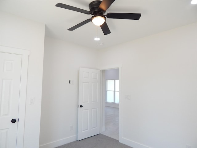 interior space with ceiling fan, baseboards, and light colored carpet