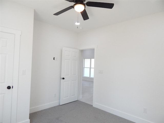 unfurnished bedroom featuring baseboards, a ceiling fan, and light colored carpet