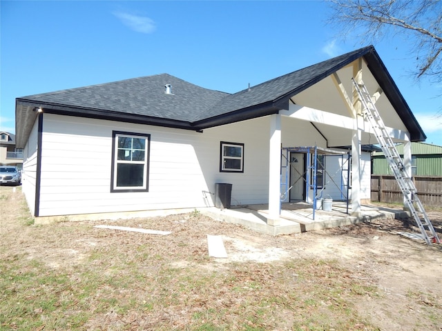 rear view of property with a shingled roof and fence